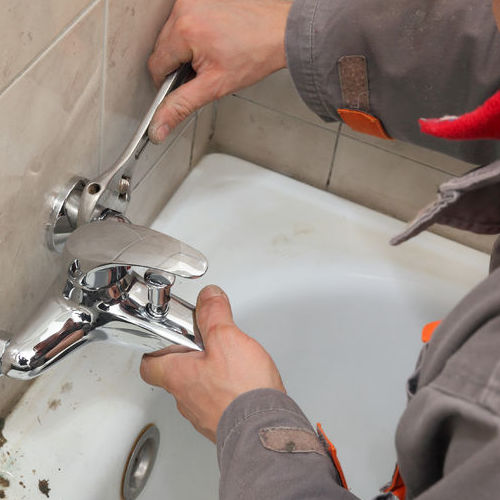 A Plumber Works on a Bathtub Faucet.