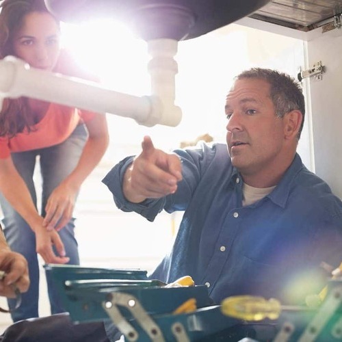 A Plumber Works on Plumbing under a Sink.